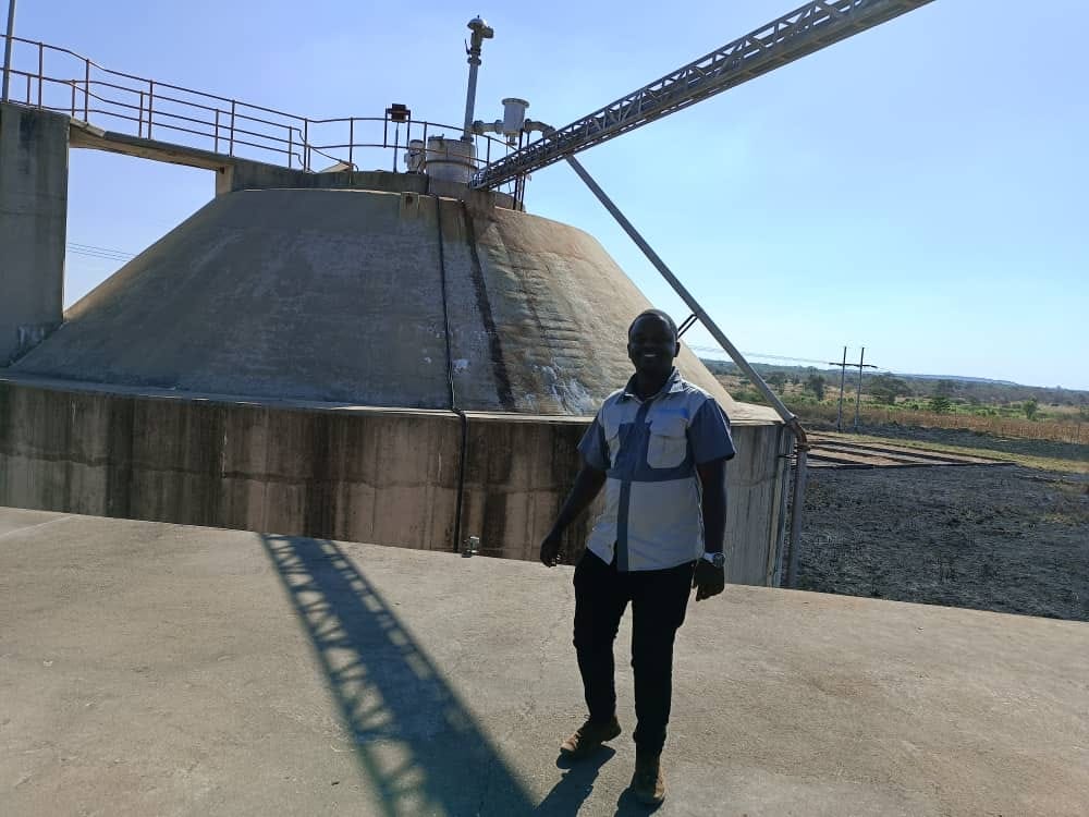 Engineer standing beside a large industrial storage silo at a mineral processing plant.
