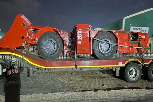 Fully rebuilt mining LHD machine, repainted and ready for redeployment, loaded on a flatbed trailer.