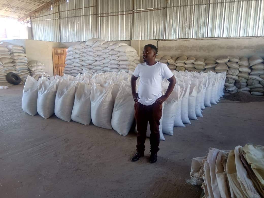 Engineer standing beside stacked sacks of processed material in a plant warehouse.