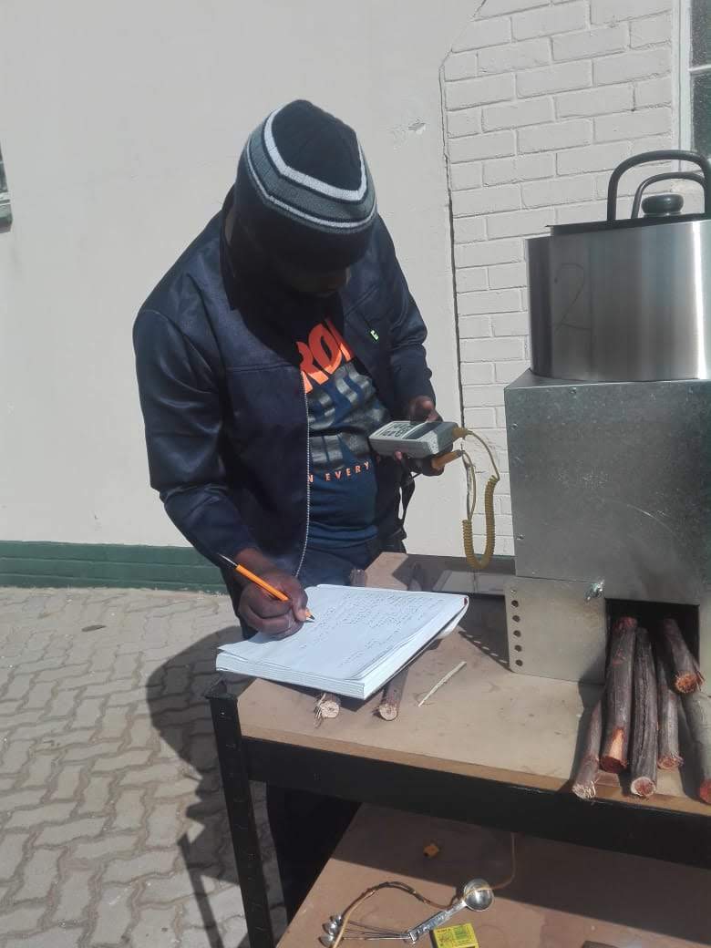 Technician in protective gear recording readings on equipment during a support visit.