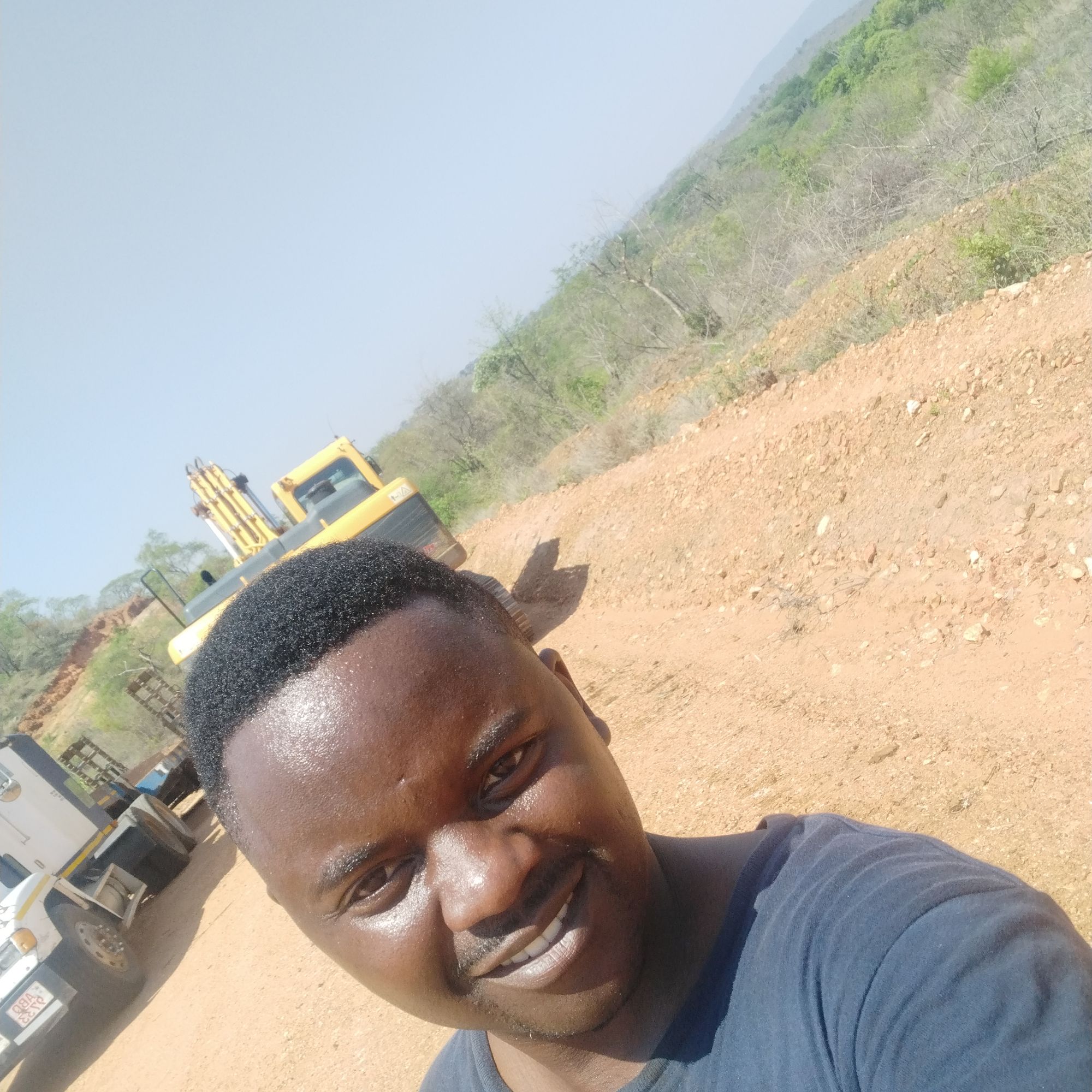 Engineer at an outdoor mining site with excavation equipment in the background.