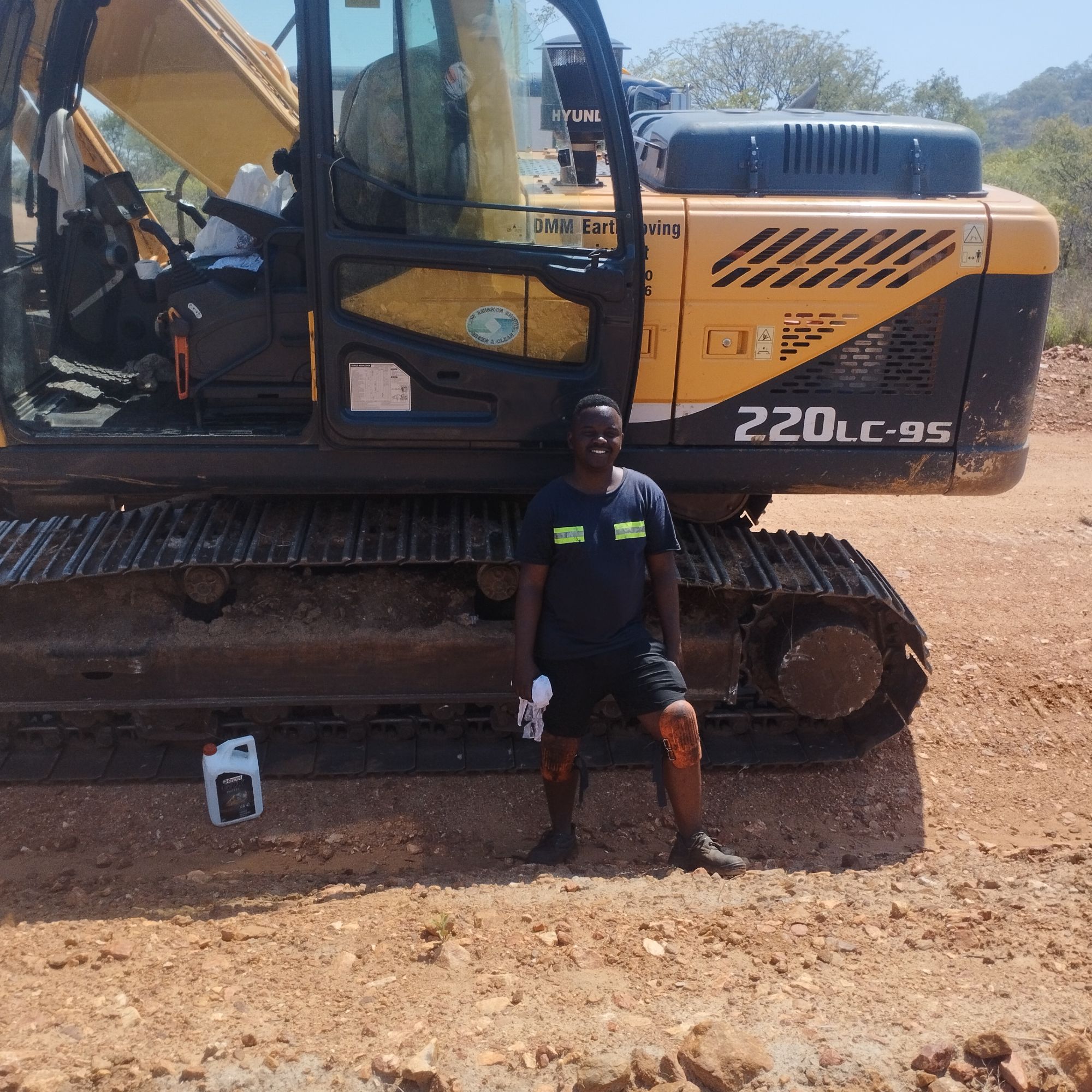 Technician crouched near the tracks of an excavator during on-site equipment support.