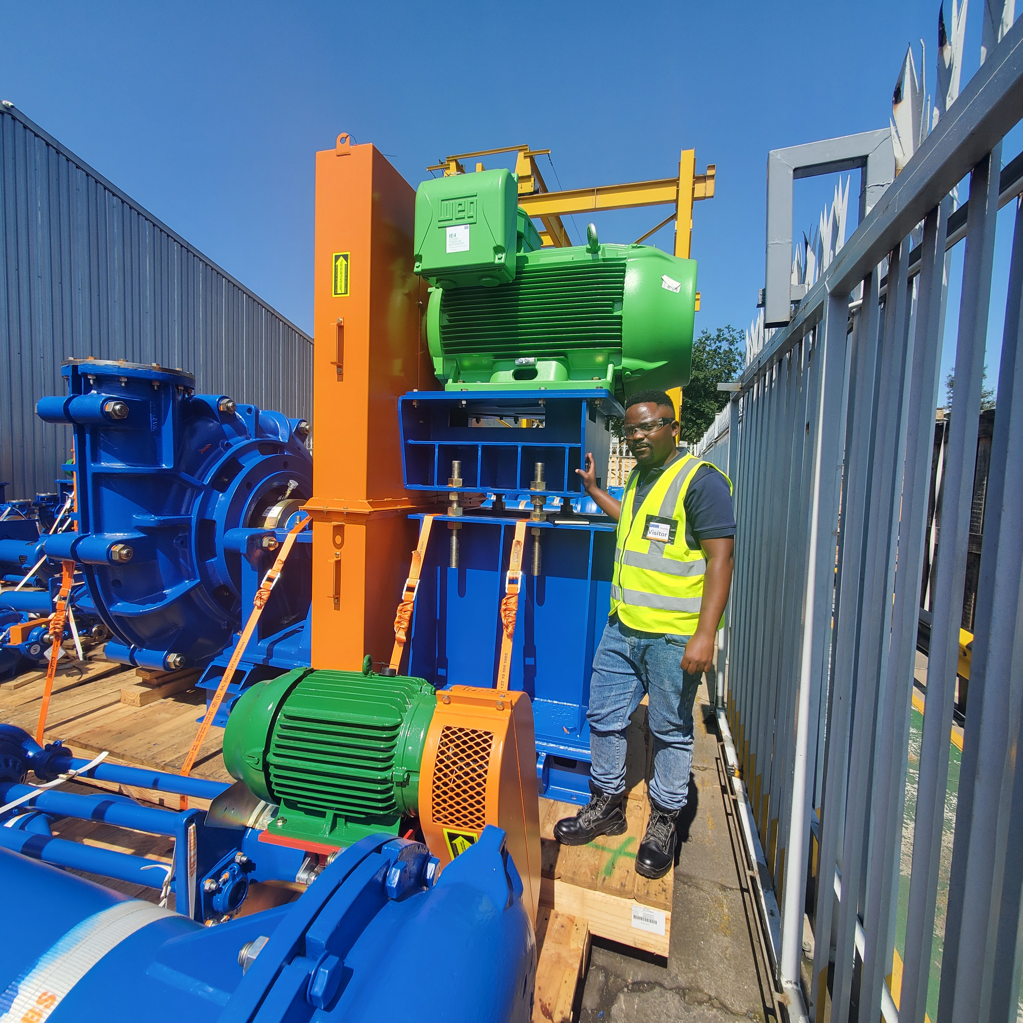 Worker beside orange and blue industrial processing equipment on-site.