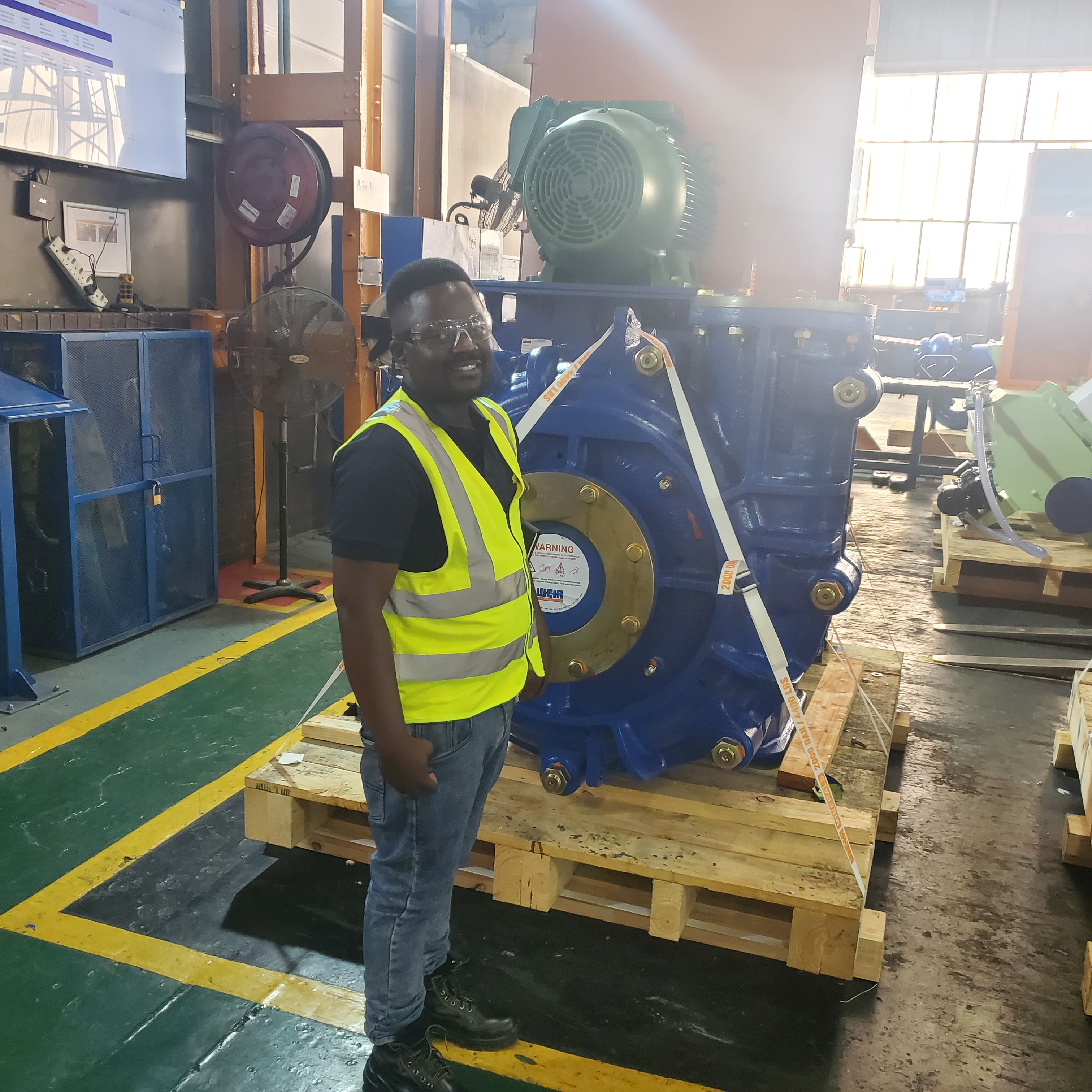 Worker in a safety vest and helmet standing on a loading platform on-site.