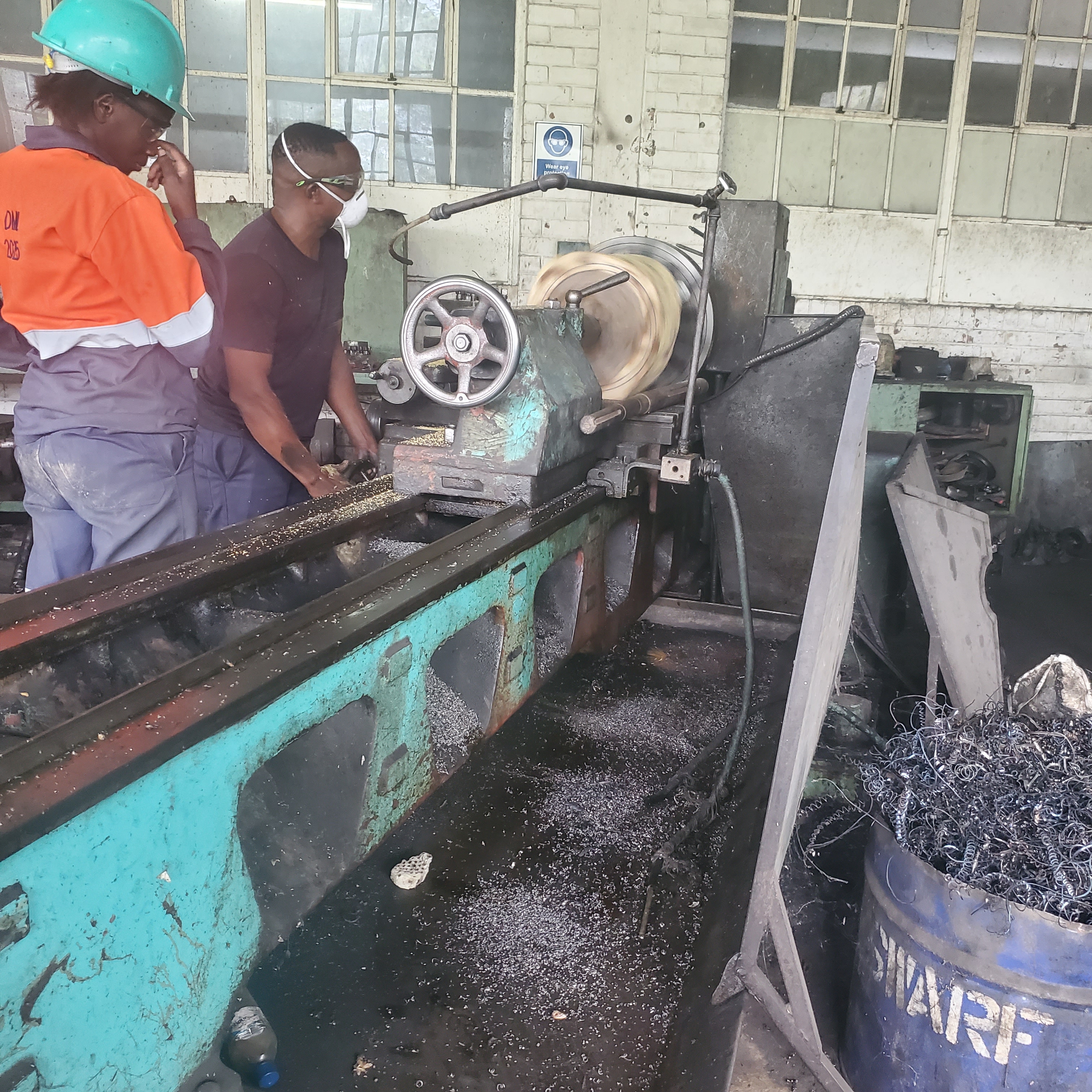 Workers servicing equipment near a mineral processing tank on-site.