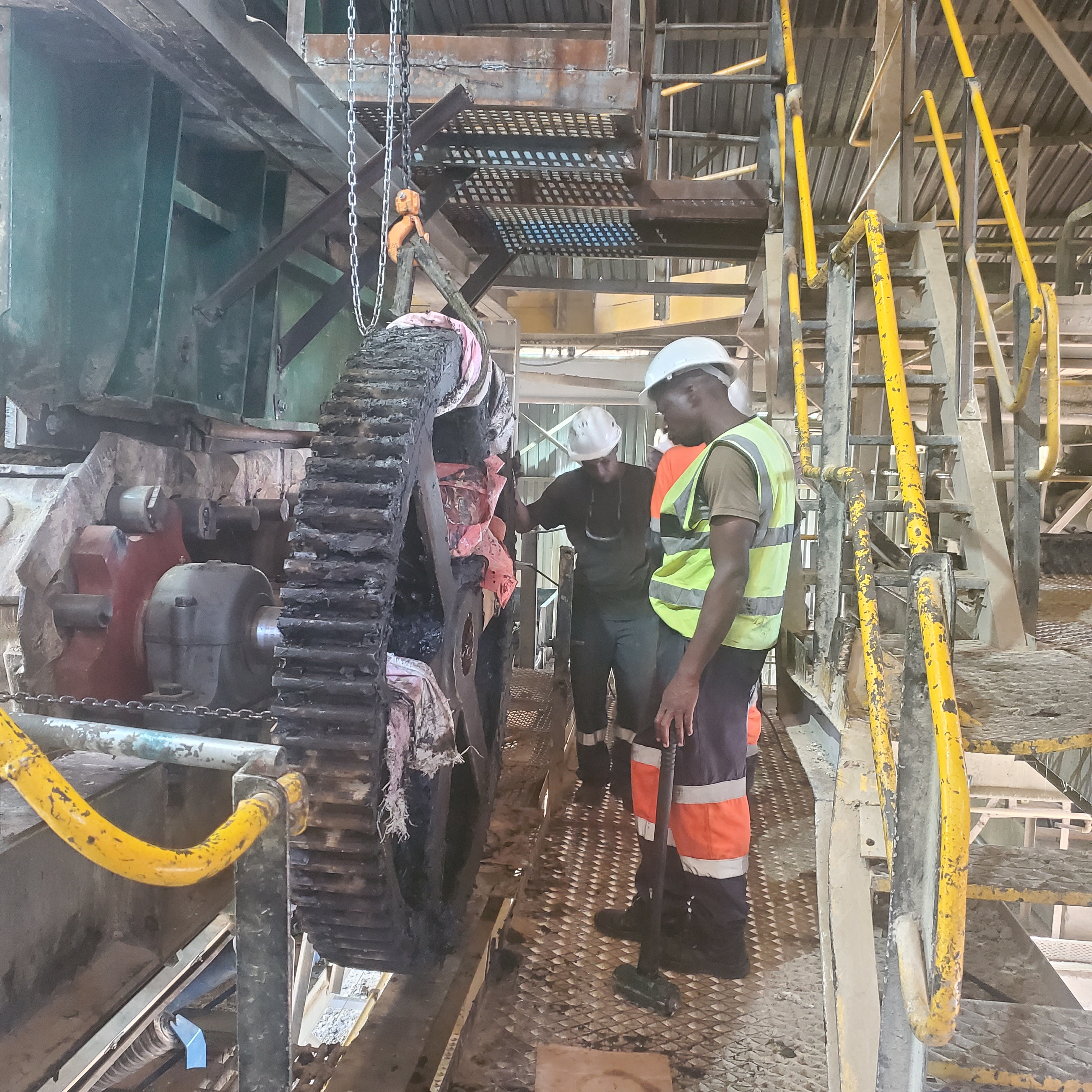 Workers in orange safety gear on an industrial structure at a project site.