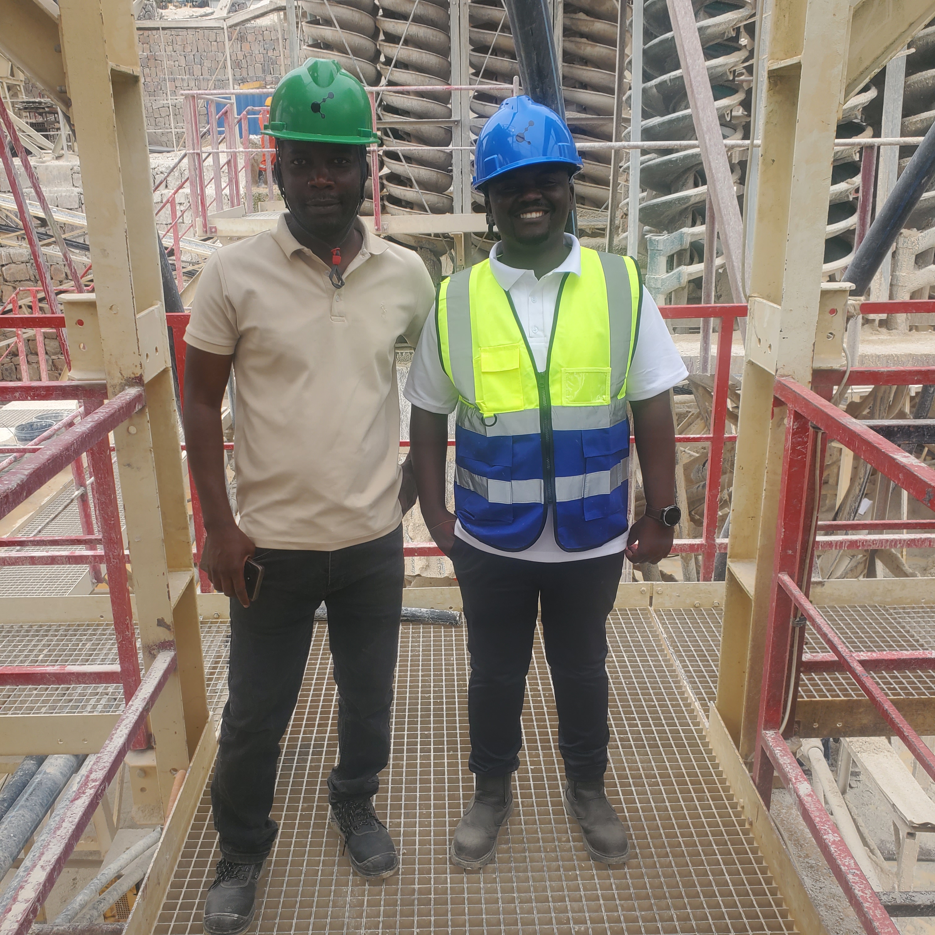 Two engineers in hard hats and safety vests standing on an elevated industrial platform.