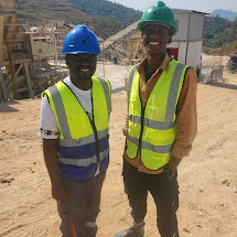 Two engineers in hard hats and safety vests at a support and maintenance site visit.