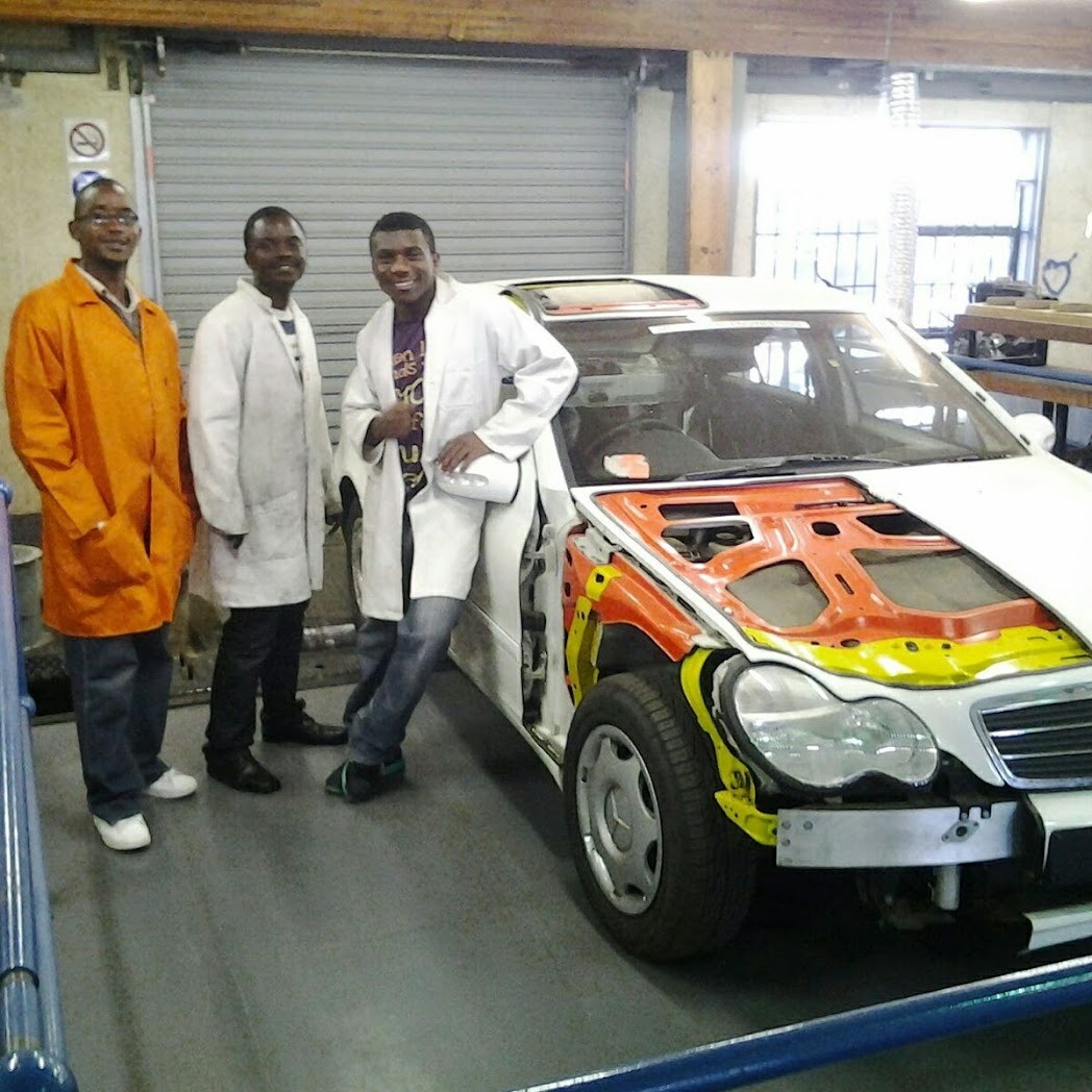 Team in lab coats beside a liveried project vehicle in a workshop.